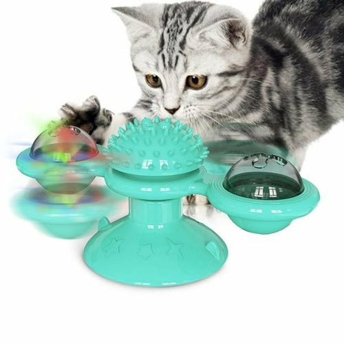 Teal spinning cat toy in motion with LED ball blur and curious cat watching