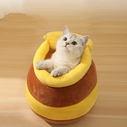 Cat sitting inside round honey pot bed with padded rim and plush interior.