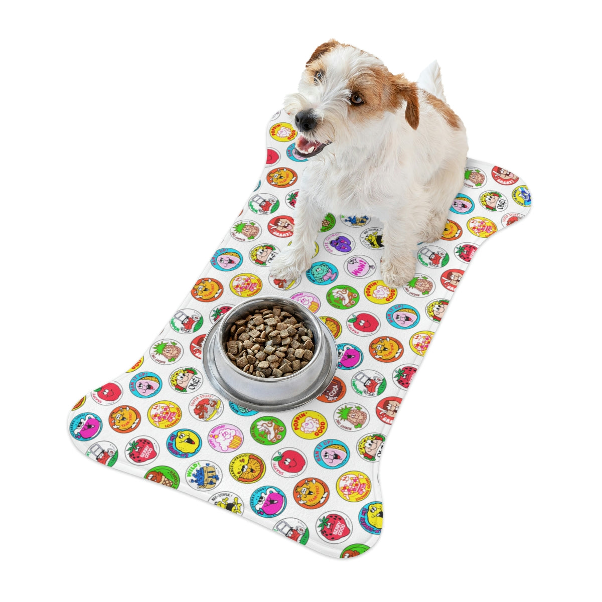 Small dog on bone-shaped pet feeding mat with colorful round cartoon print and steel food bowl.
