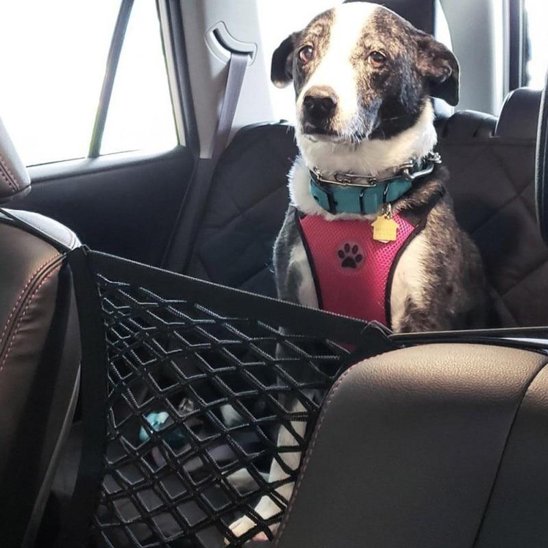 Black and white dog sitting calmly behind the Pawfy Land mesh seat barrier in an SUV.