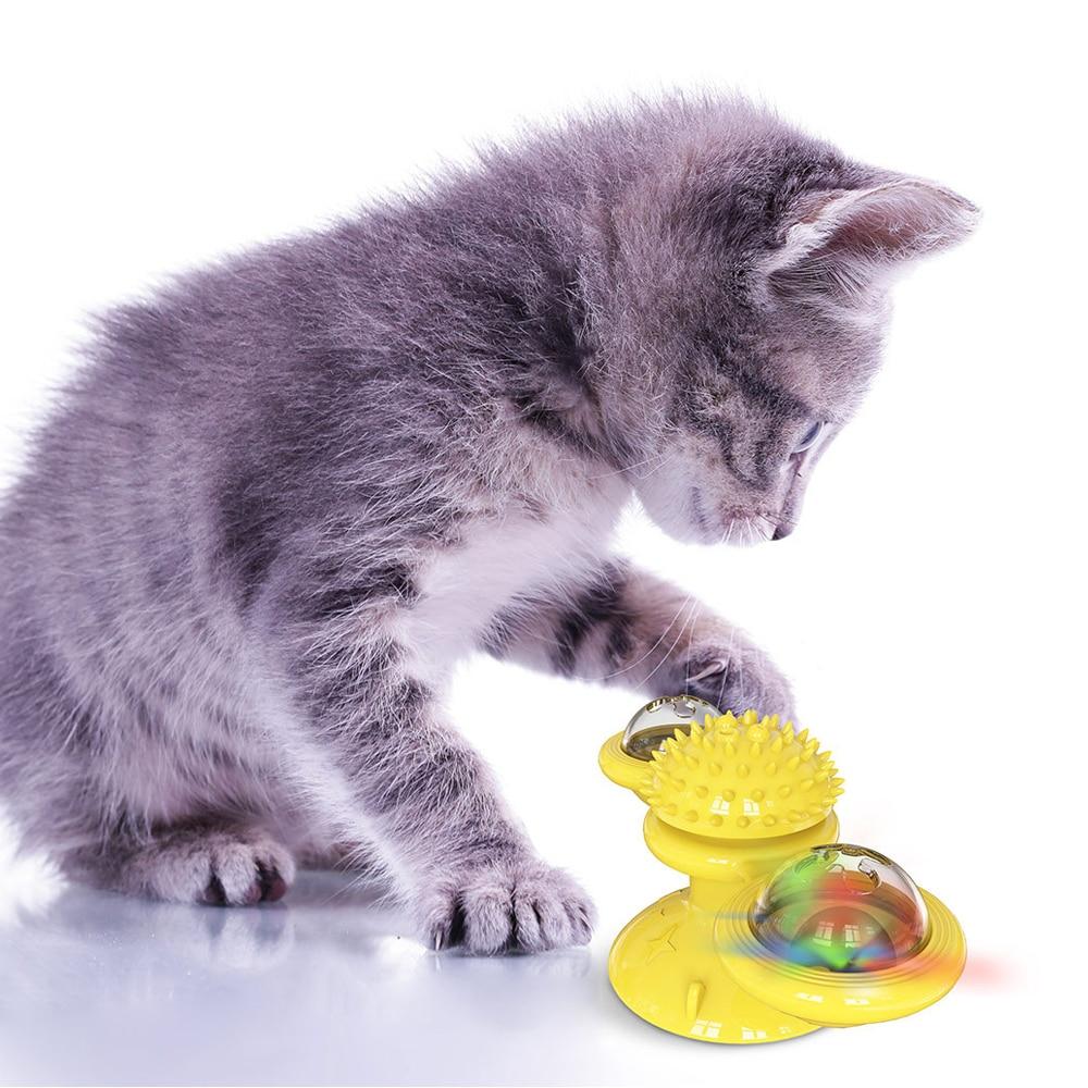 Gray kitten pawing at yellow spinning cat toy with LED ball and spiky center